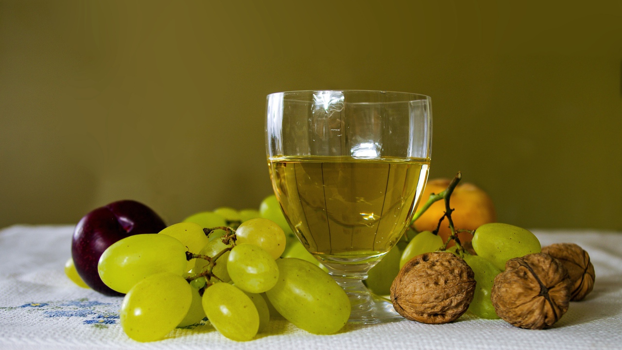 Бокал белого вина на столе с виноградом и орехами