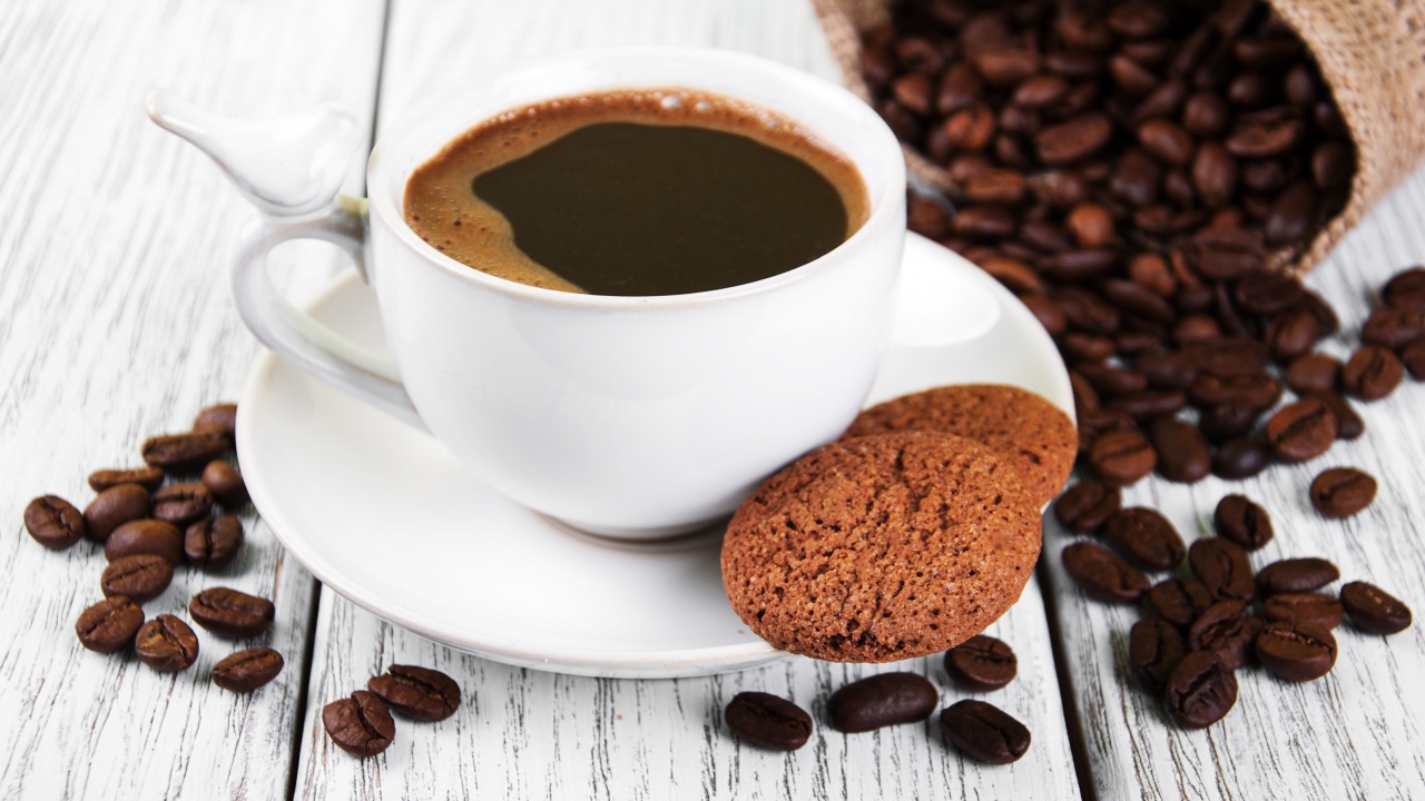 Чашка кофе на столе с кофейными зернами и печеньем