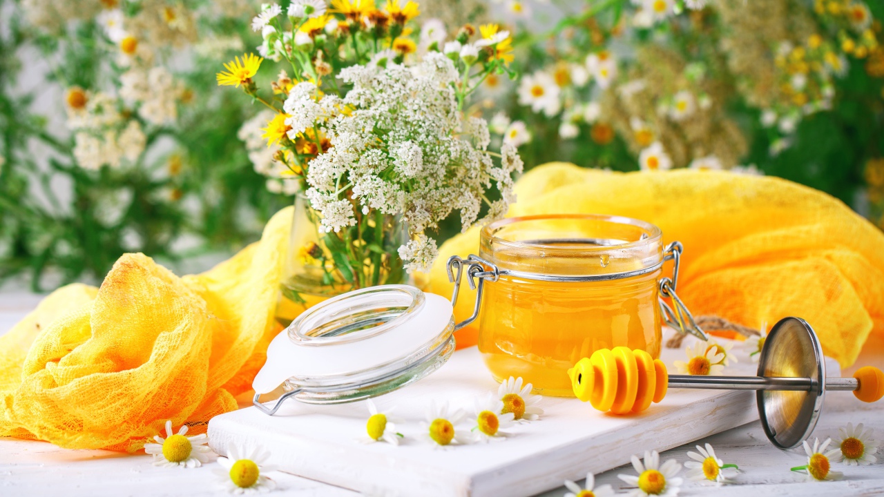 Банка меда на столе с цветами