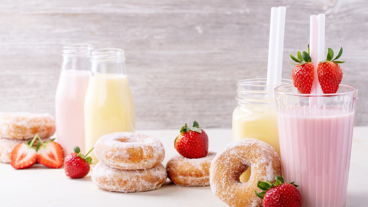 Молочные коктейли на столе с клубникой и пончиками
