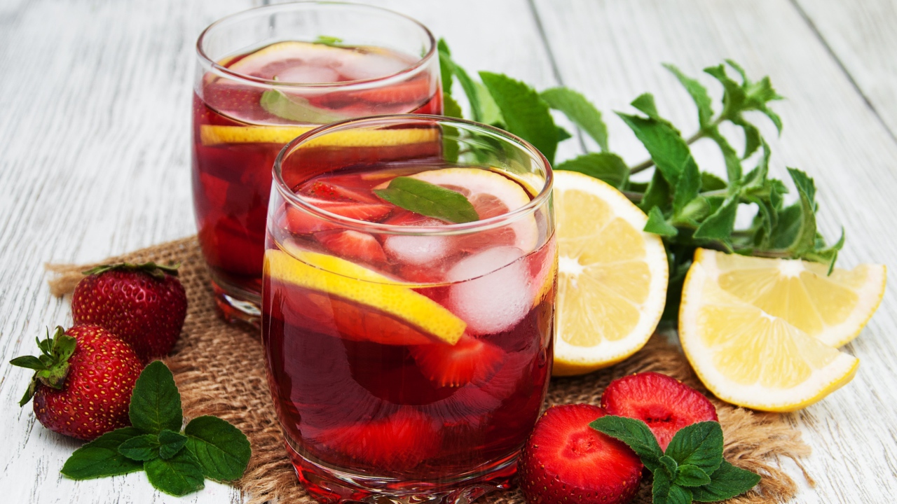 Мохито в стаканах на столе с клубникой, лимоном и мятой