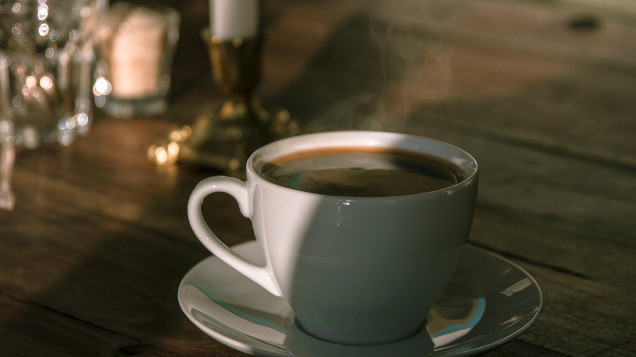 Белая чашка кофе на столе в лучах солнца