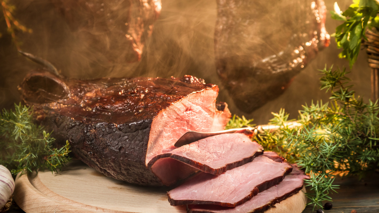 Аппетитный кусок сочной ветчины нарезан на разделочной доске