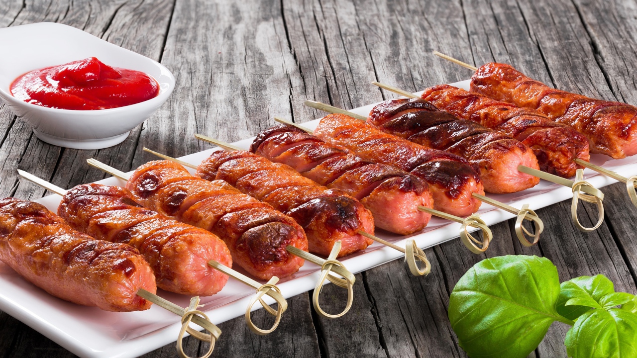 Сосиски гриль на шпажках на столе с соусом