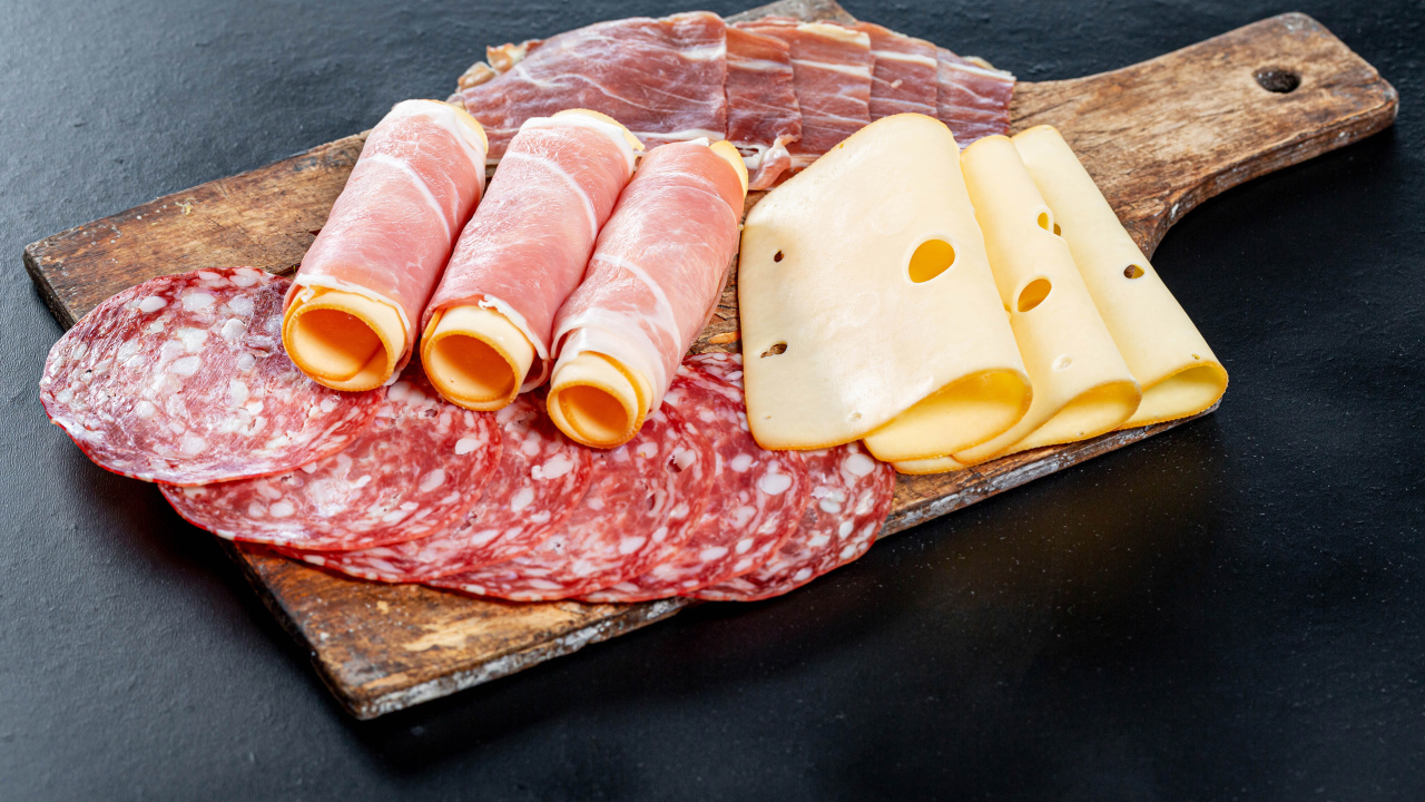 Ветчина на доске с колбасой и твердым сыром