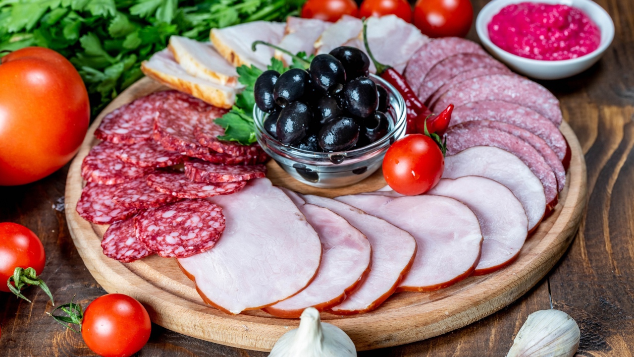 Колбасные продукты на доске с оливками