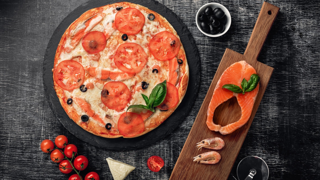 Пицца с помидорами, красной рыбой и сыром на столе 