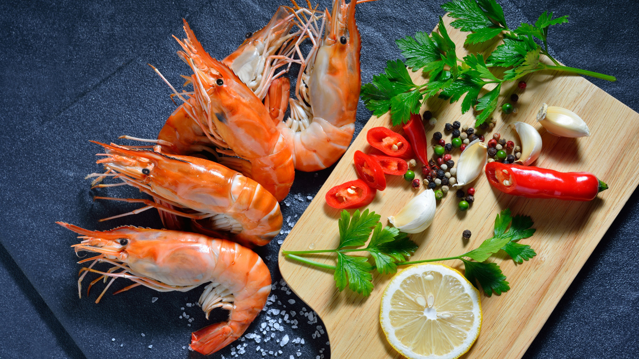 Вареные креветки на столе со специями и зеленью