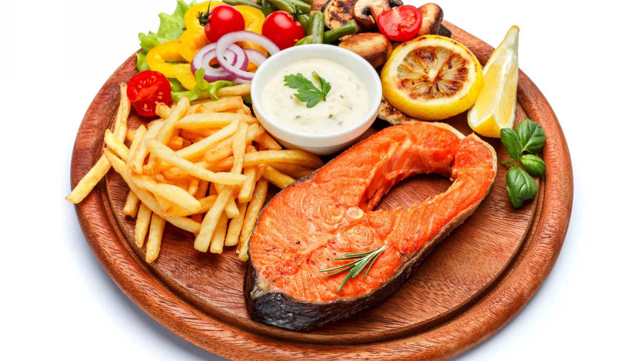 Рыба на доске с картофелем фри, овощами и соусом
