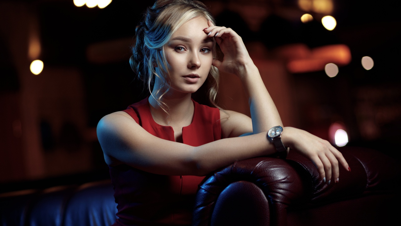 Красивая девушка с часами на руке сидит в кресле