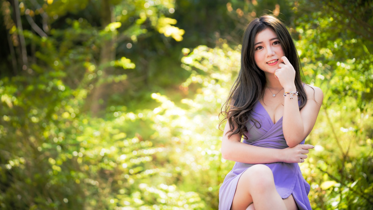 Молодая девушка азиатка сидит на лавке в парке