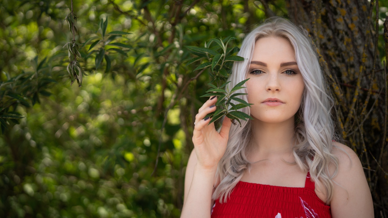 Красивая блондинка стоит у дерева 