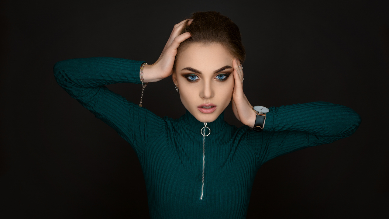 Красивая голубоглазая девушка в зеленом свитере на черном фоне