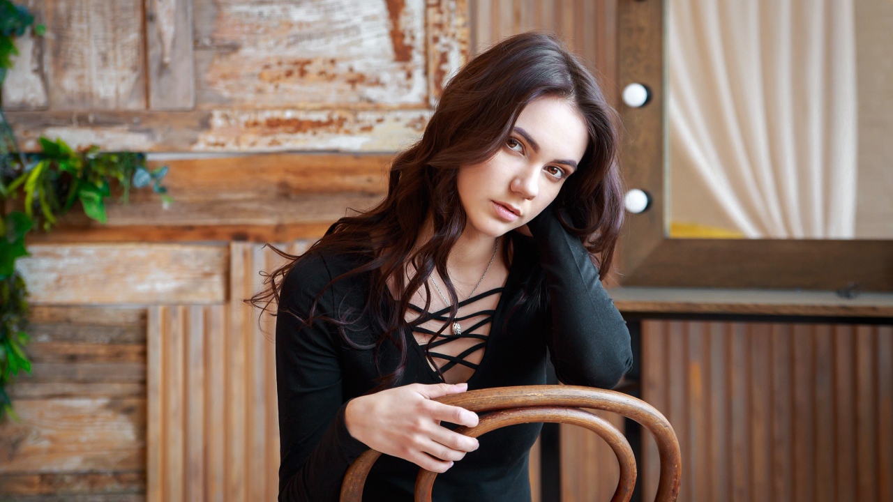 Красивая кареглазая девушка сидит на стуле