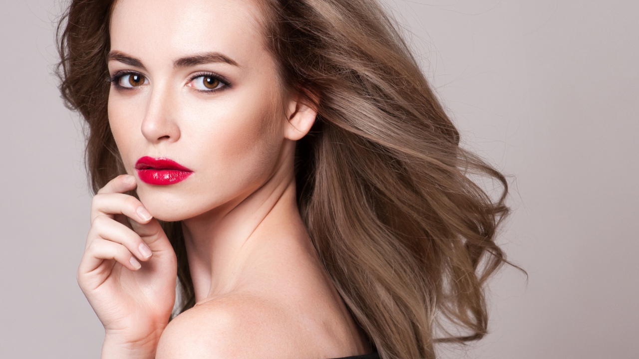 Красивая шатенка с красными губами на сером фоне