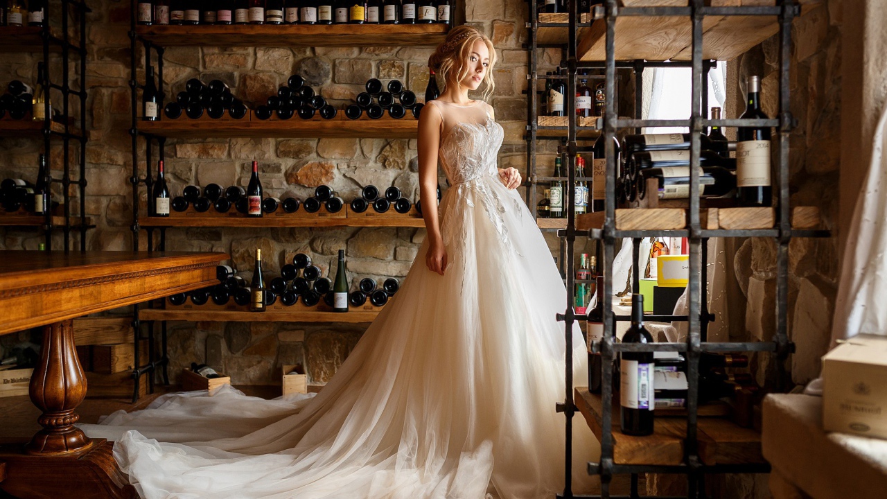 Красивая девушка в пышном свадебном платье в винном погребе