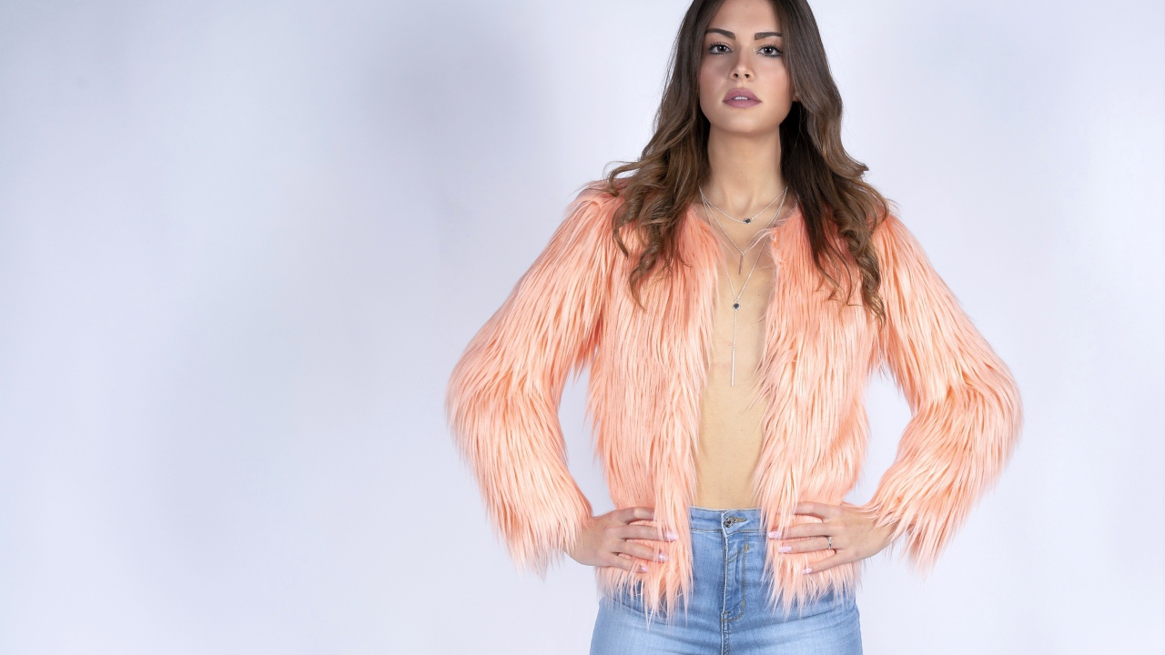 Красивая девушка в розовой шубе и джинсовых шортах