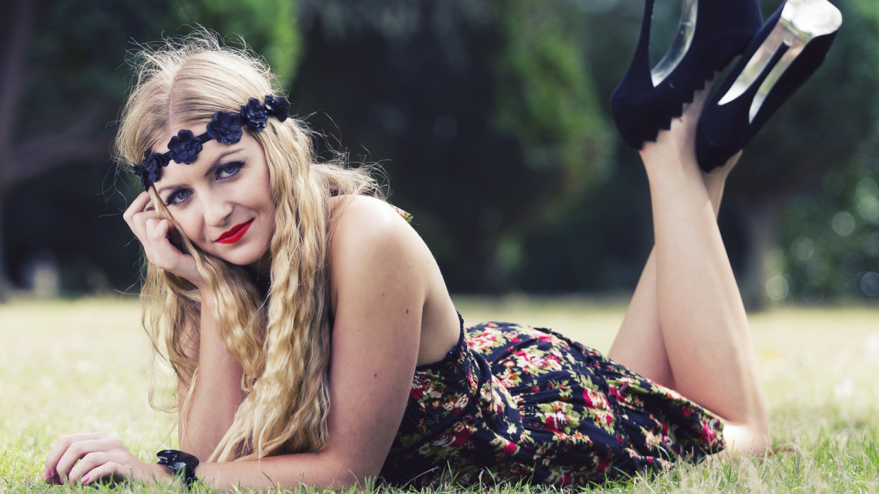 Красивая девушка в черных туфлях лежит на зеленой траве