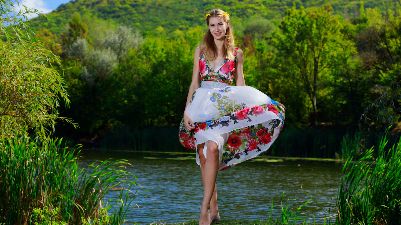 Красивая девушка в платье у реки на фоне леса 