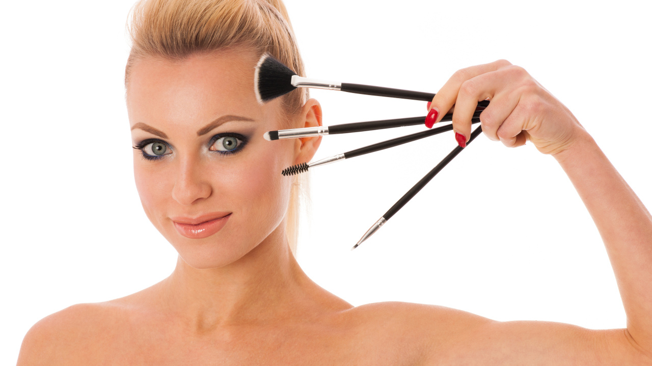 Красивая девушка с кистями для макияжа на белом фоне