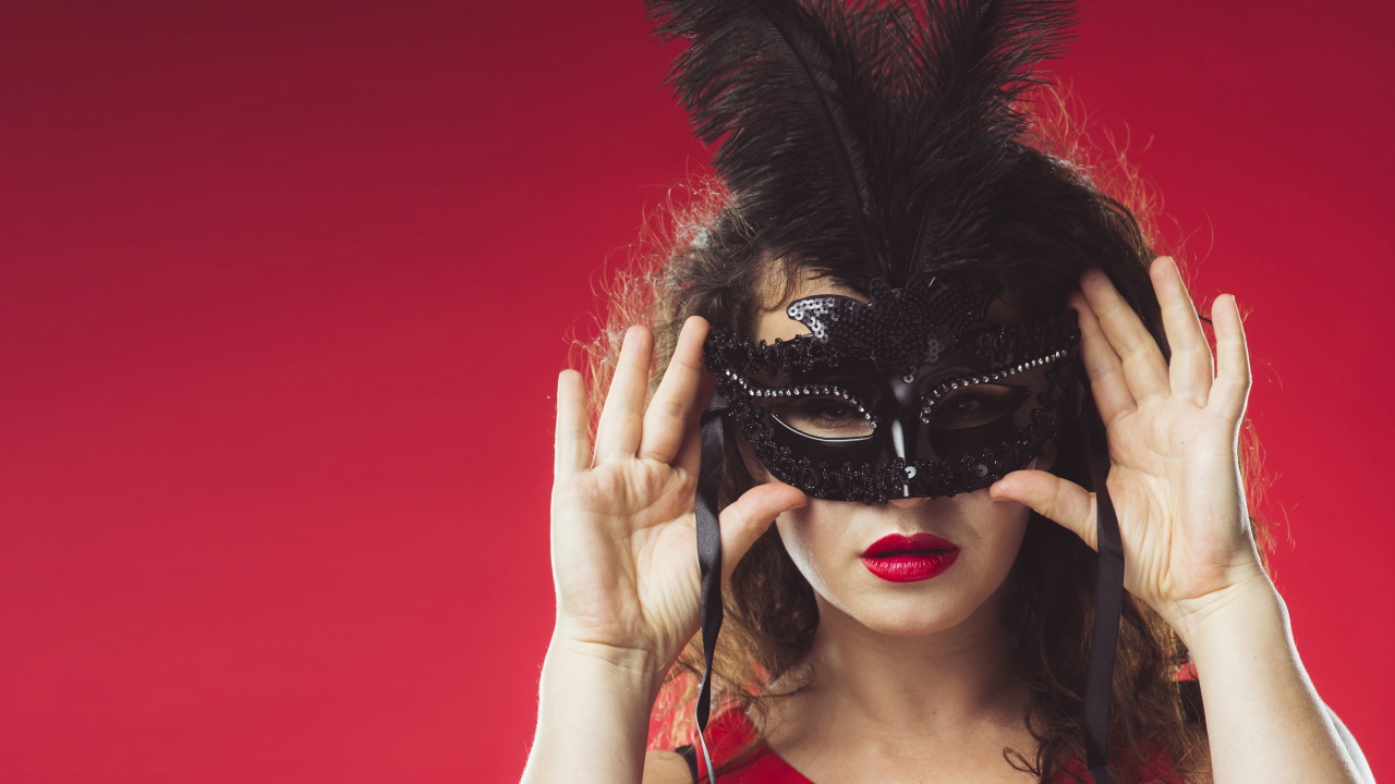 Красивая женщина в черной маске на красном фоне