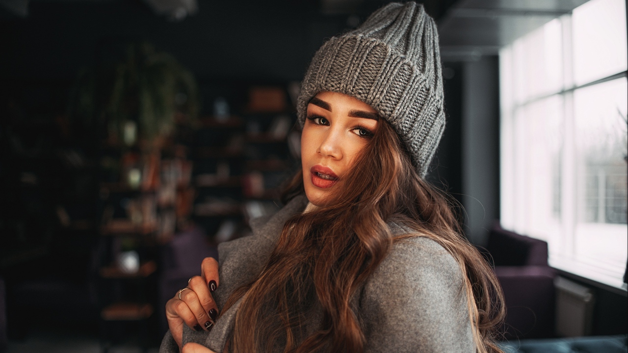 Красивая молодая девушка в пальто в вязаной шапке