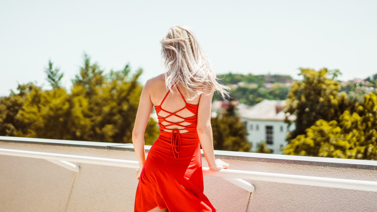 Красивая молодая девушка в красном платье на балконе