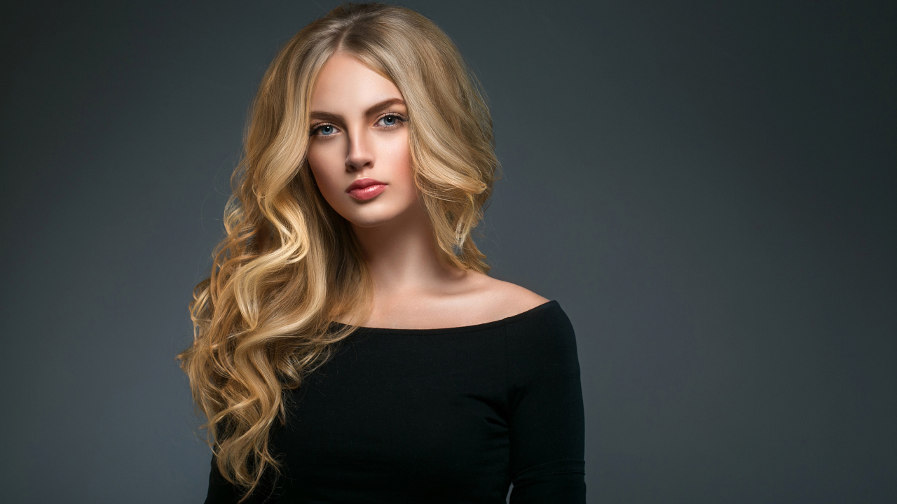 Красивая молодая девушка с длинными волосами в черном наряде на сером фоне