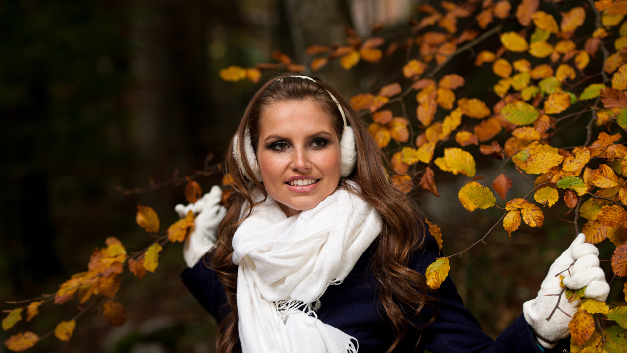 Девушка шатенка с белым шарфом стоит у дерева с желтыми листьями