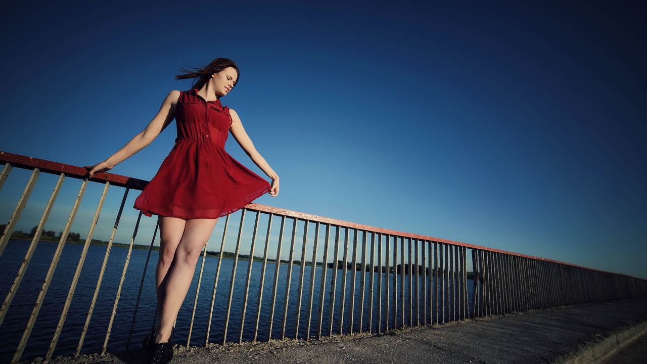 Девушка в коротком красном платье на мосту 