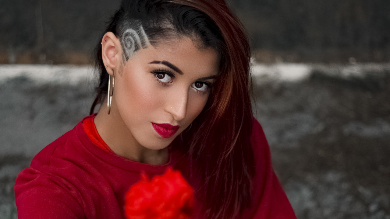 Девушка со стрижкой держит розу в руке