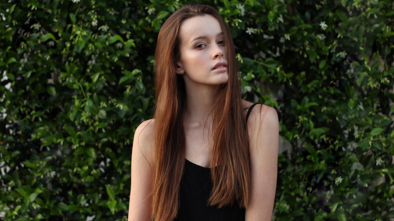 Длинноволосая шатенка на фоне зеленых зарослей