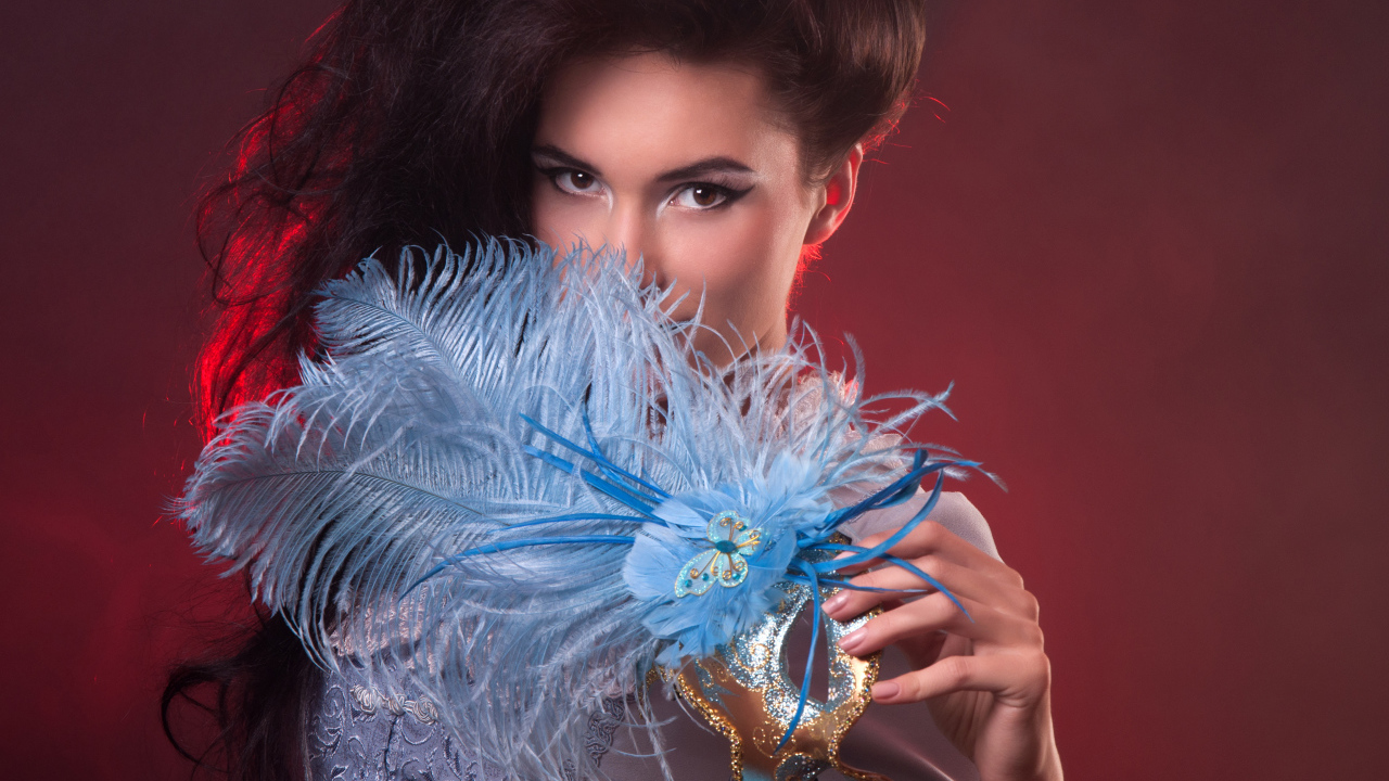 Длинноволосая девушка с маской с перьями в руке
