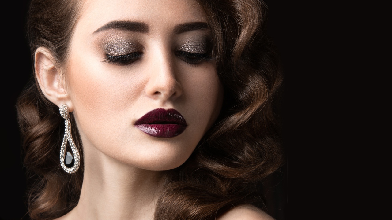 Длинноволосая девушка с ярким макияжем на черном фоне