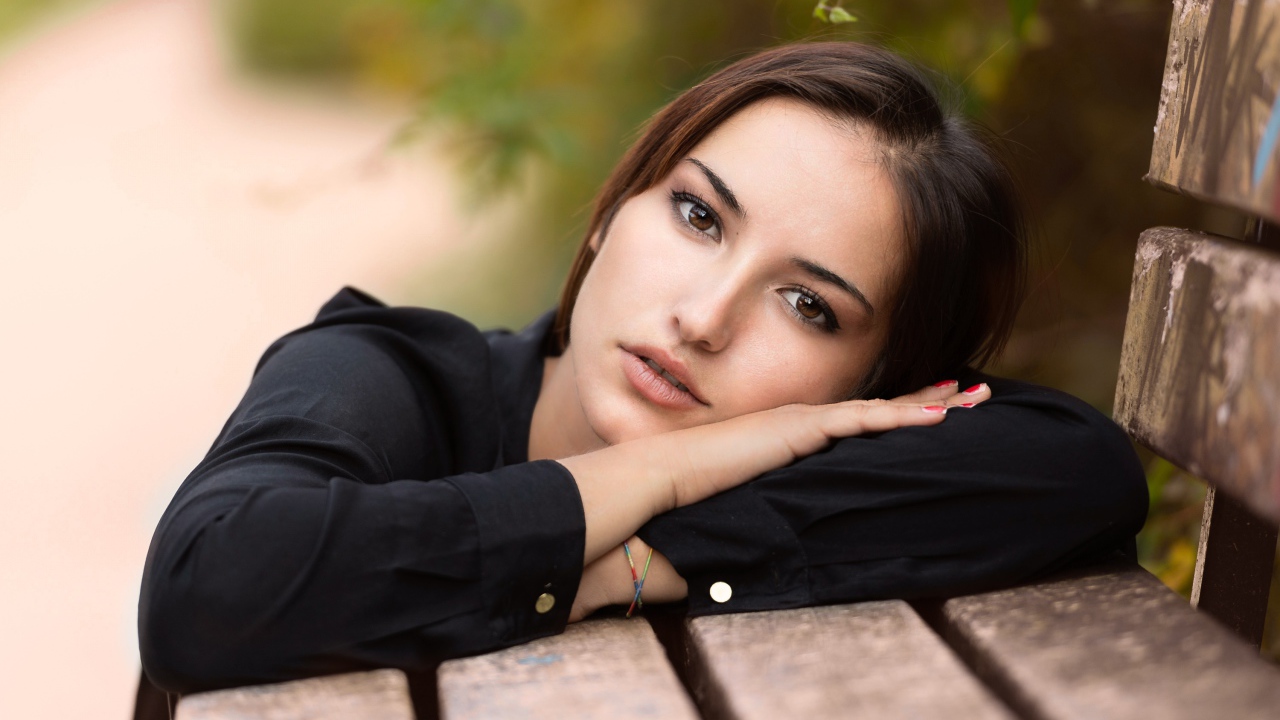 Грустная кареглазая девушка лежит на деревянной лавке