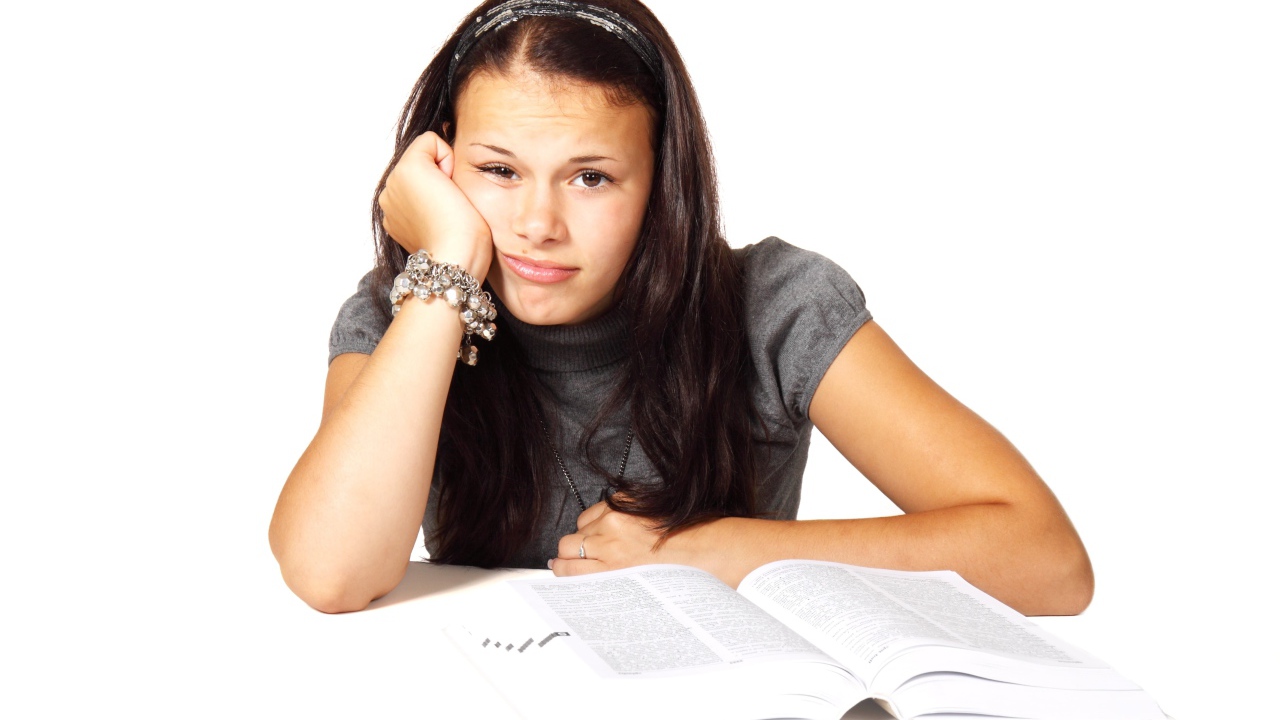 Грустная девушка читает книгу на белом фоне