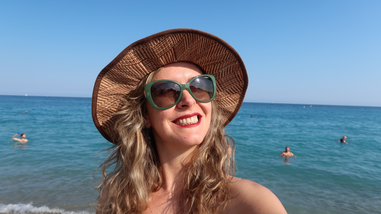 Улыбающаяся девушка в солнечных очках и шляпе на море