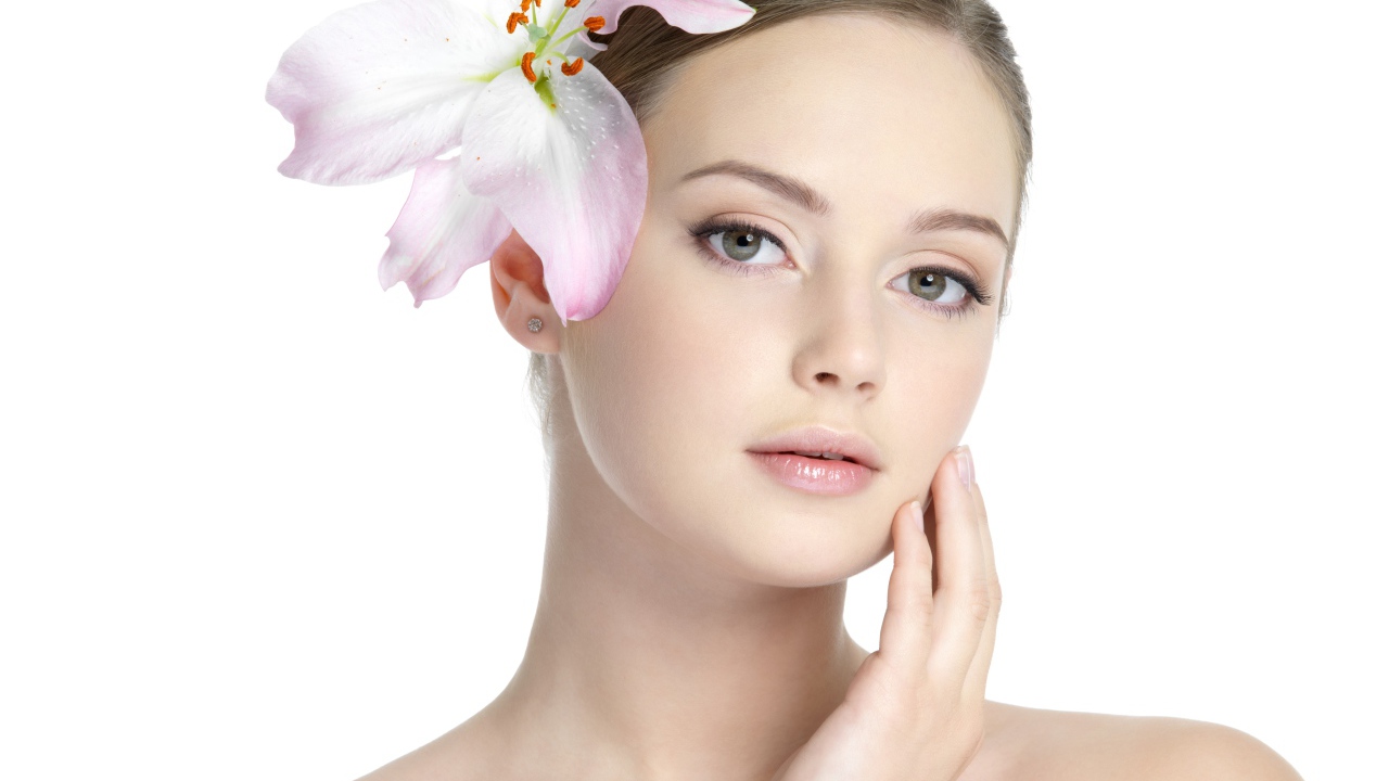 Нежная красивая девушка с лилией в волосах на белом фоне 