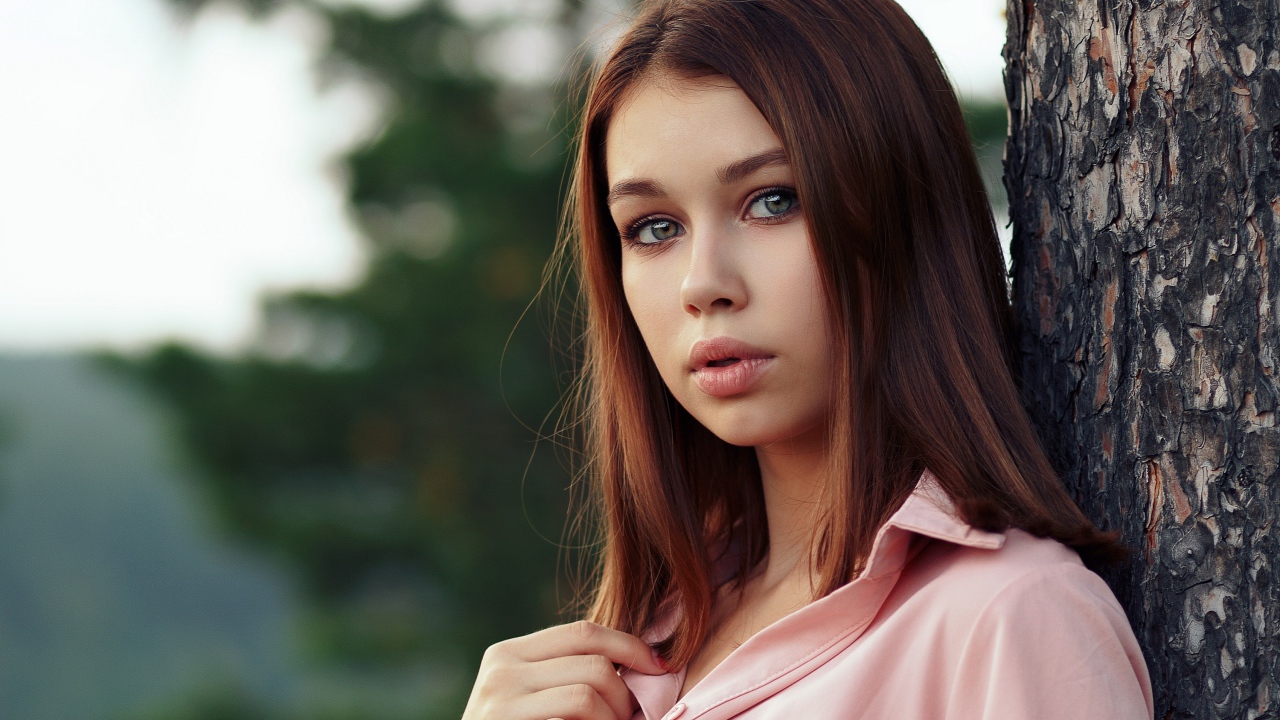 Нежная девушка стоит у дерева