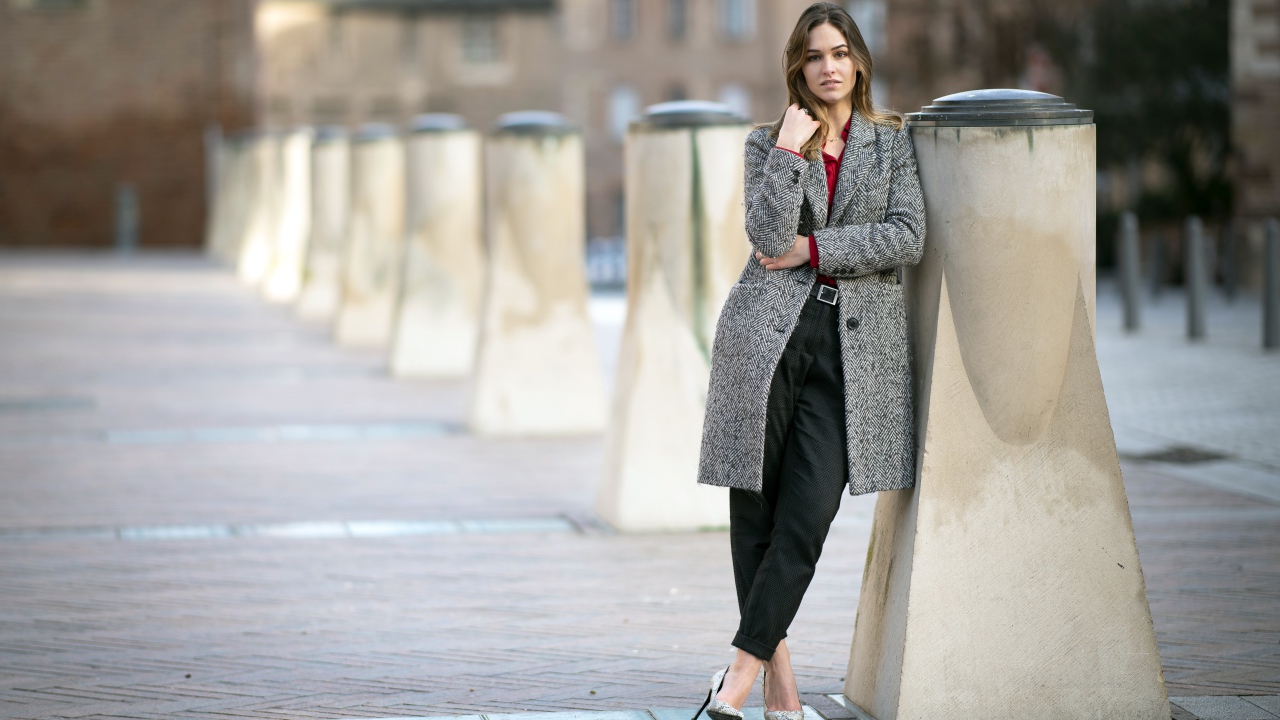 Девушка стоит в сером пальто 