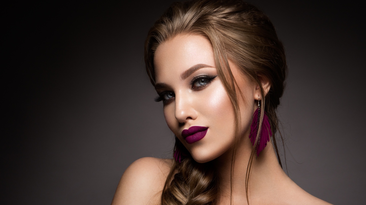 Девушка с ярким макияжем и косой на сером фоне