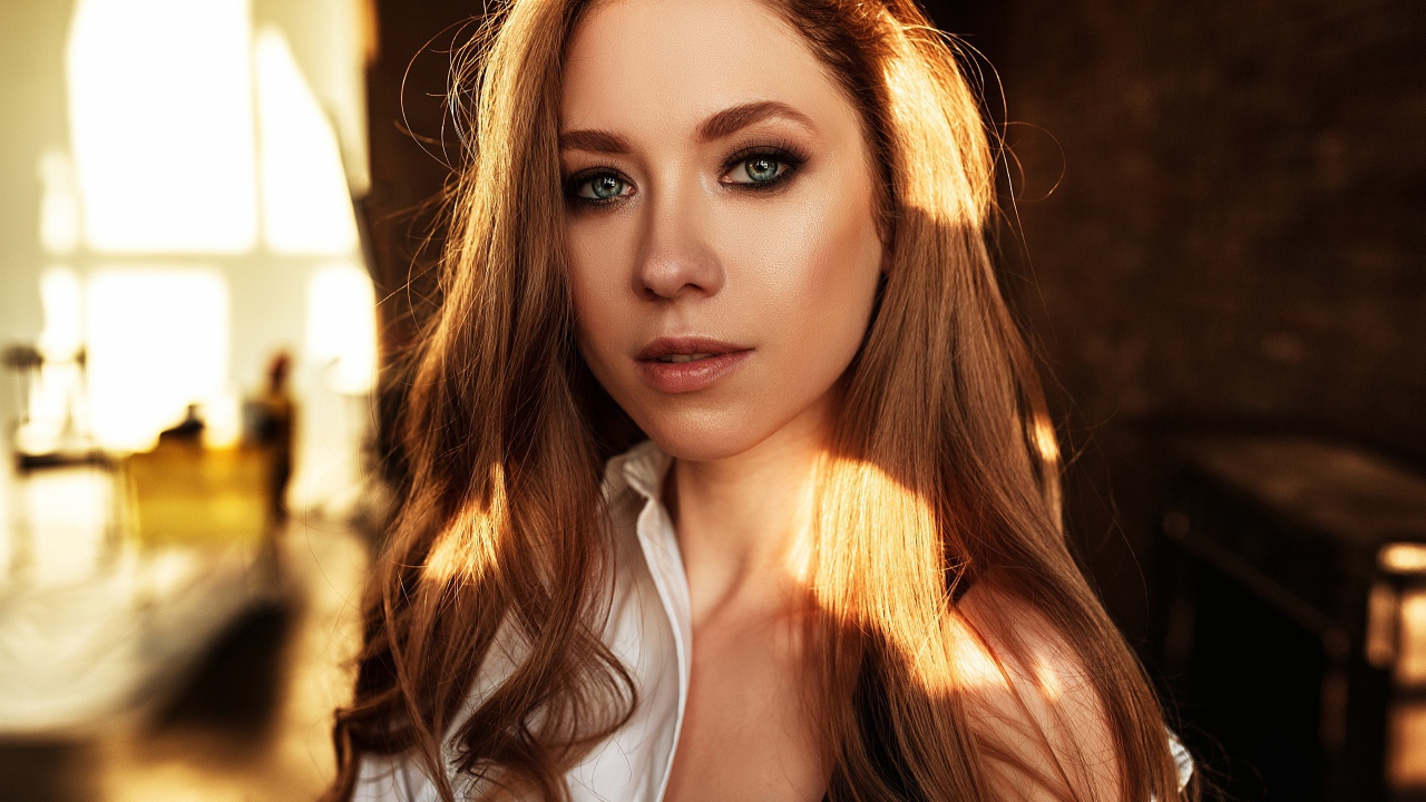 Лучи солнца нападают на волосы голубоглазой шатенки 
