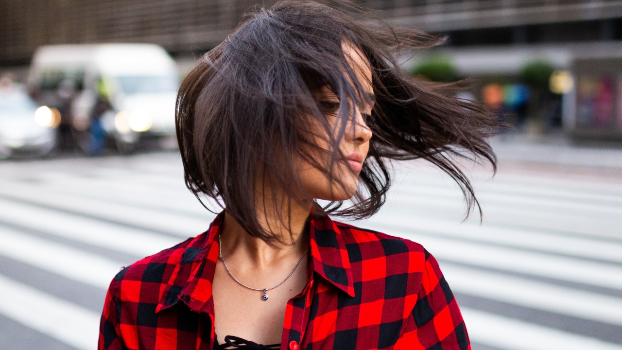 Ветер развивает волосы красивой шатенки в клетчатой рубашке