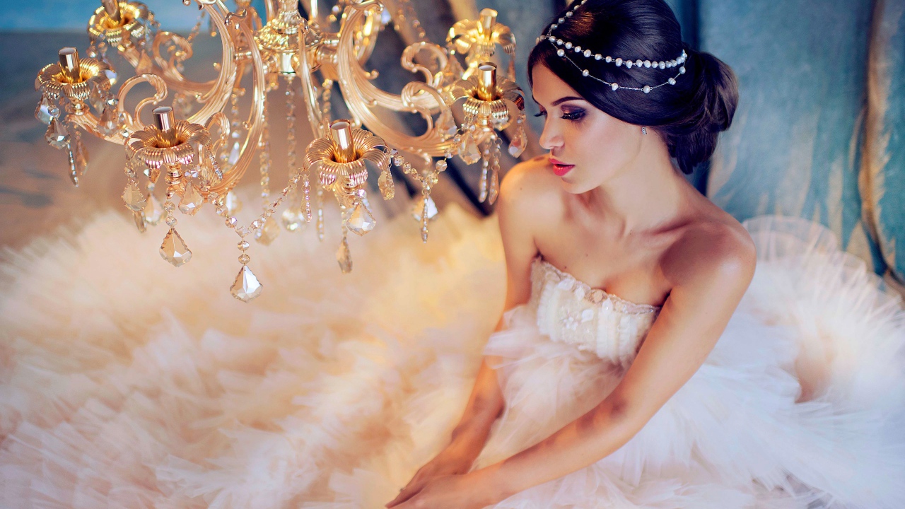 Молодая девушка в белом платье у красивой  люстры