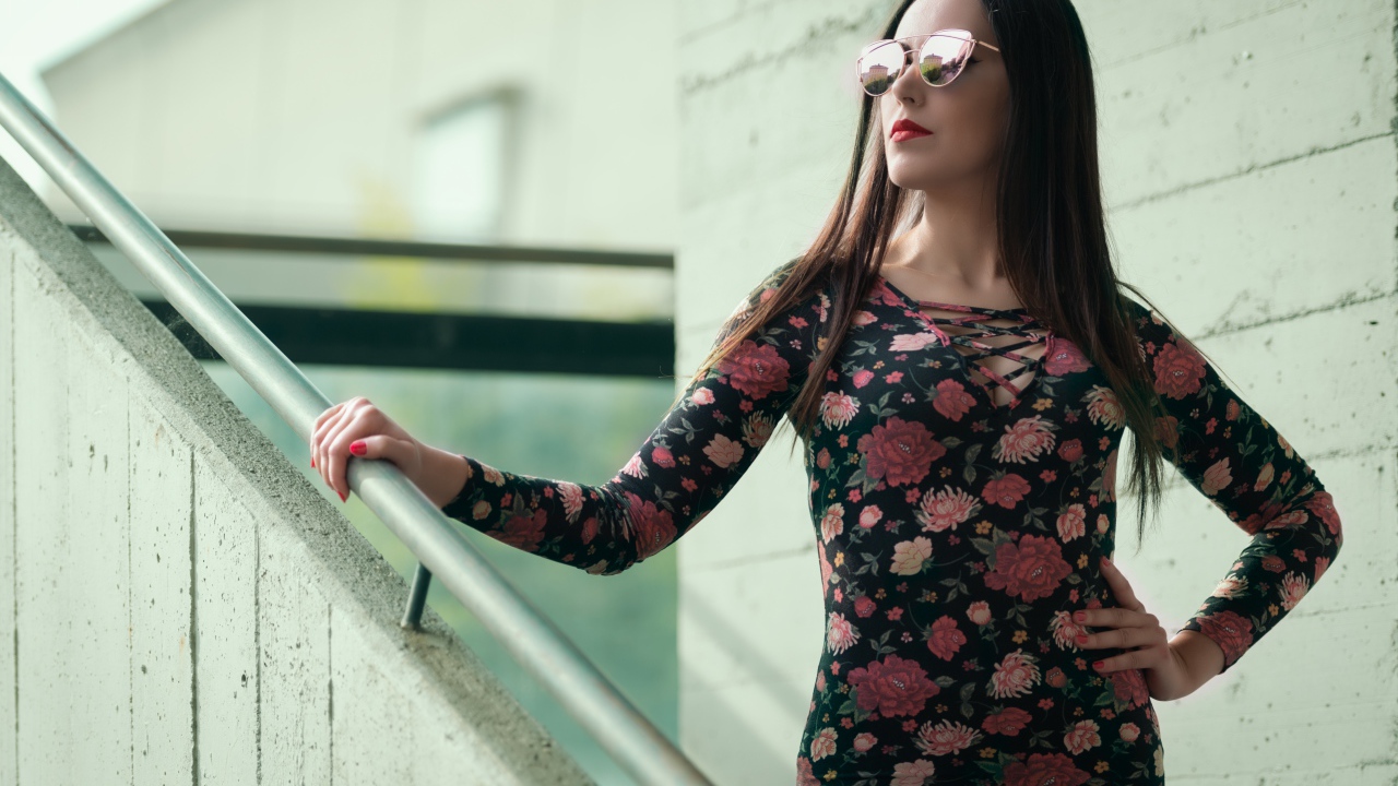 Молодая девушка в солнечных очках стоит на ступеньках