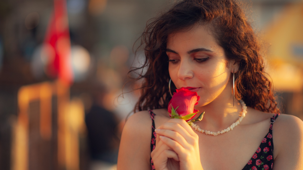 Молодая нежная девушка с красной розой в руке