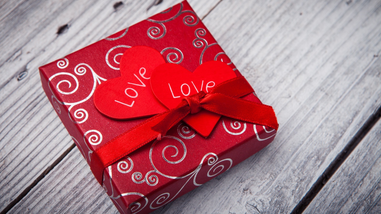 Подарок с красными сердечками на деревянном столе 