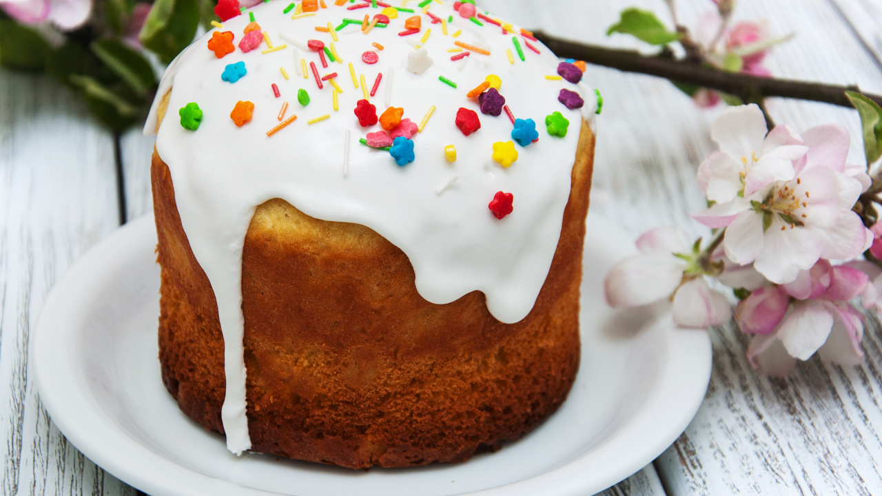 Красивый кулич с белой глазурью на столе с веткой яблони на Великий праздник Пасха