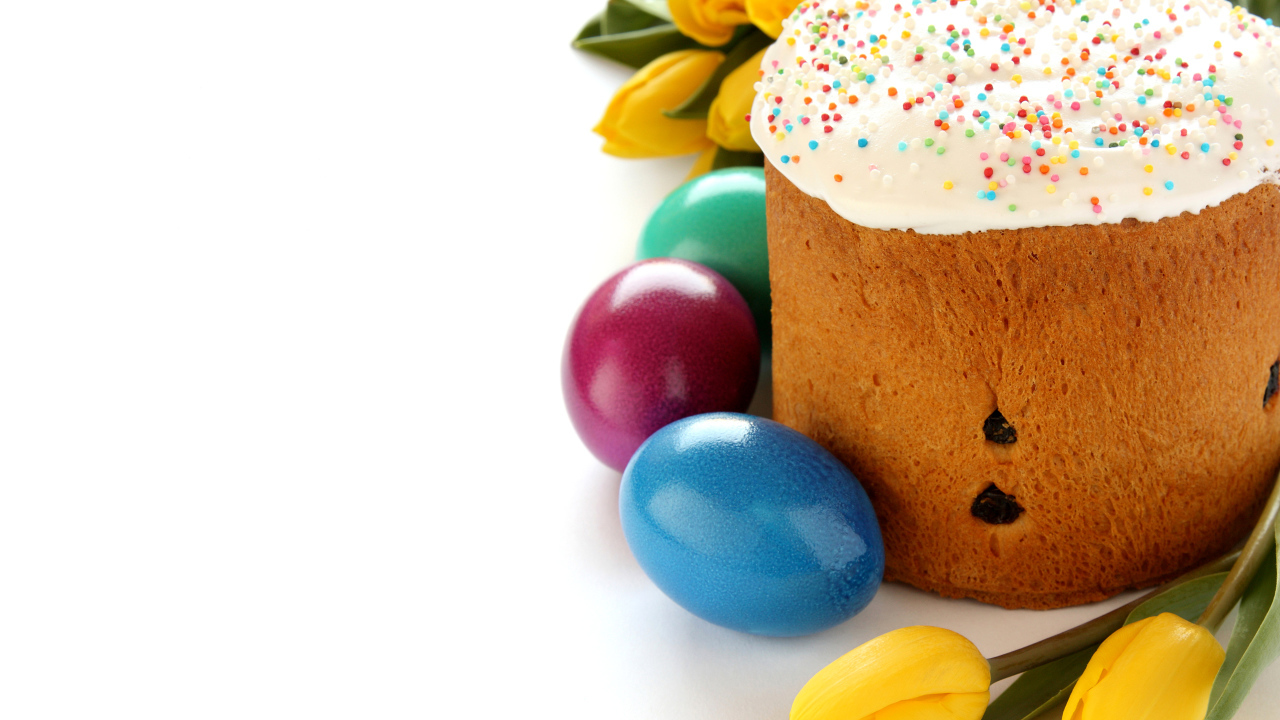 Красивый праздничный кулич с желтыми тюльпанами и крашеными яйцами на белом фоне к Пасхе