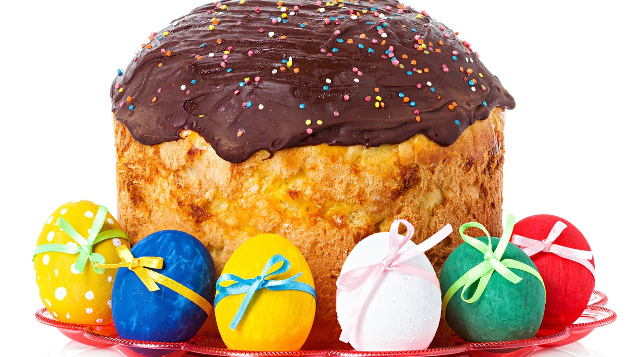 Большой пасхальный кулич с шоколадной глазурью на белом фоне с крашеными яйцами 